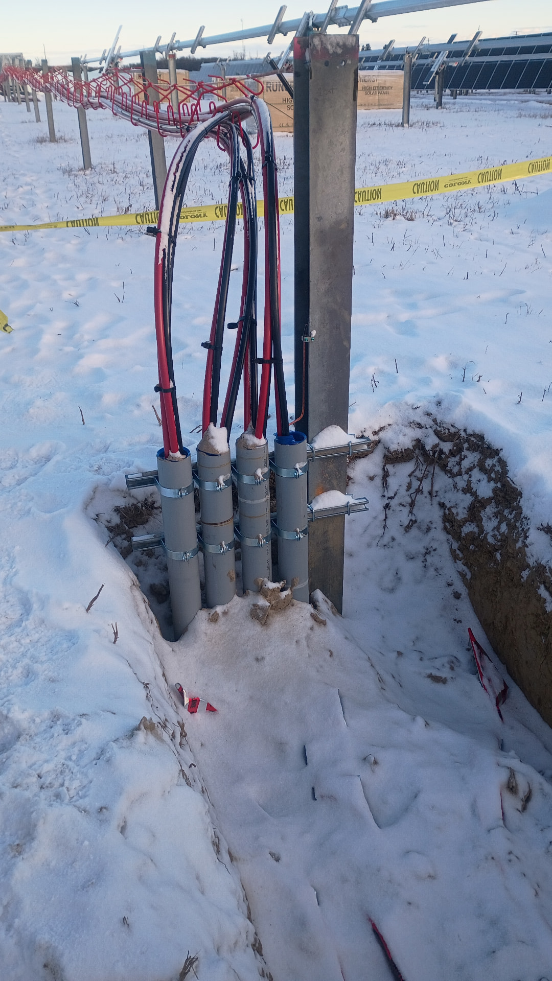 Feeder conduit terminations rising from a trench at a solar array