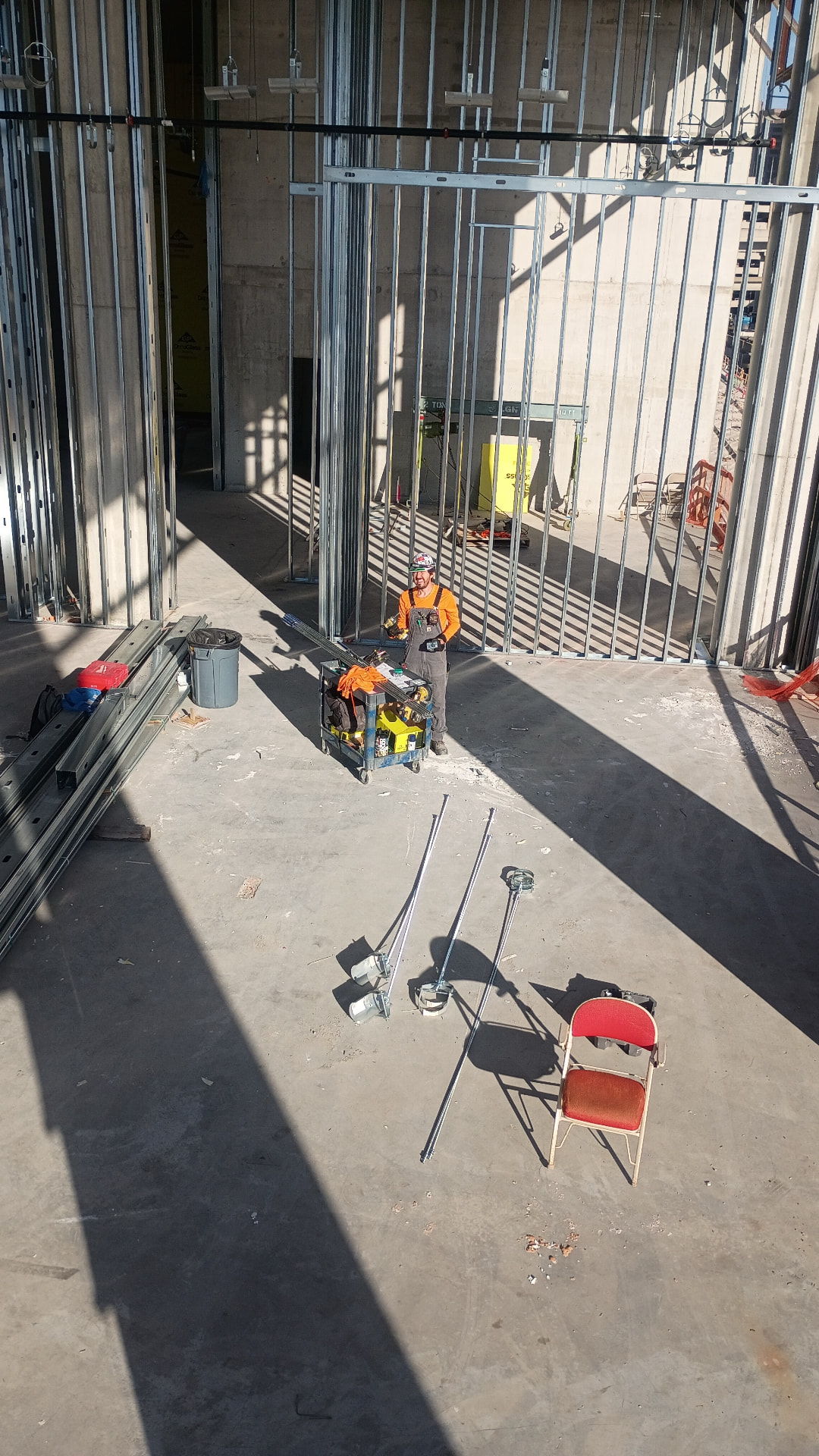 High-rise interior with metal stud framing and conduit runs staged on the floor for installation
