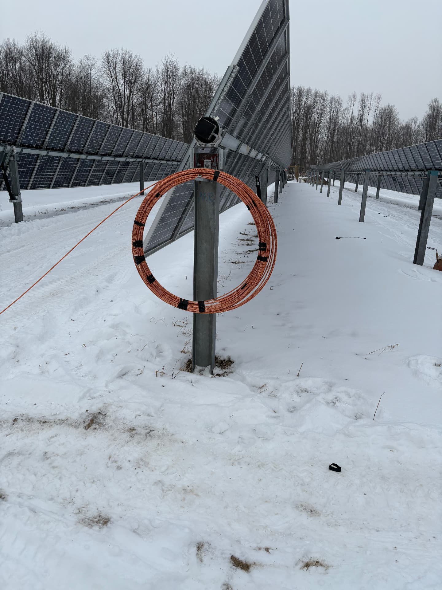 Solar panel array with coiled PV wire staged on a tracker post