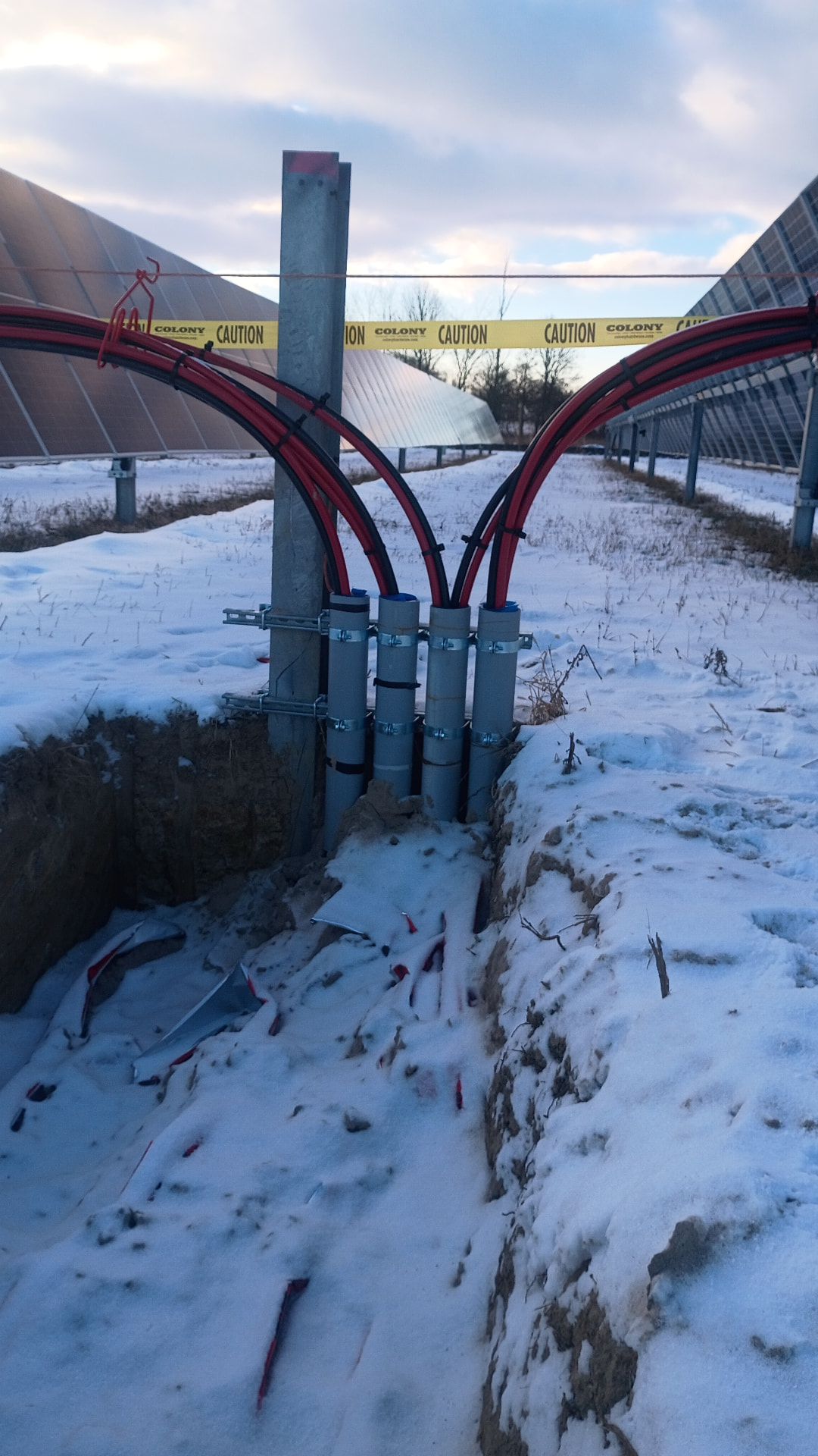 Underground DC feeder conduit risers in an open trench at a solar site